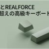 HHKBとREALFORCEの高級キーボード比較を示すアイキャッチ用スライド。淡いグリーン背景にキーキャップとスペースバー風の立体パーツが配置されている。